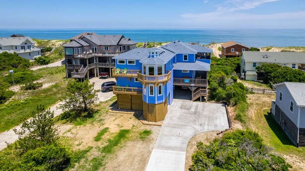 A coastal residential area with multiple houses, including a prominent blue house with a tower-like structure.