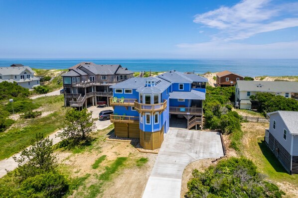 A coastal residential area with multiple houses, including a prominent blue house with a tower-like structure.