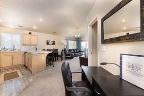 A modern kitchen with a dining area, a large mirror, and a welcome sign.