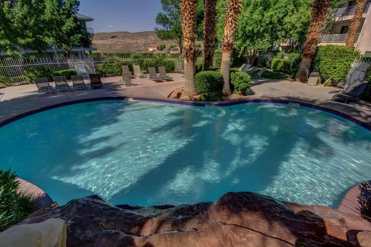 A swimming pool with lounge chairs and palm trees.