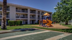 A courtyard with a children's play area, including a slide and swings, and a shuffleboard court.