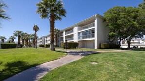 A multi-story hotel with a central courtyard, palm trees, and a clear sky. - Las Palmas Resort #1616 | All-Inclusive Amenities (Saint George)