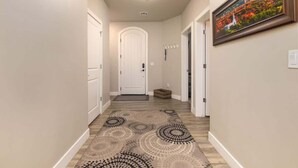 Un corridoio con una moquette decorata, una porta bianca e un quadro appeso al muro.