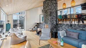 A modern living room with a fireplace, a dining area with chairs, and a sofa.