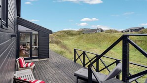 A wooden deck with outdoor seating and a glass door leading to a room.