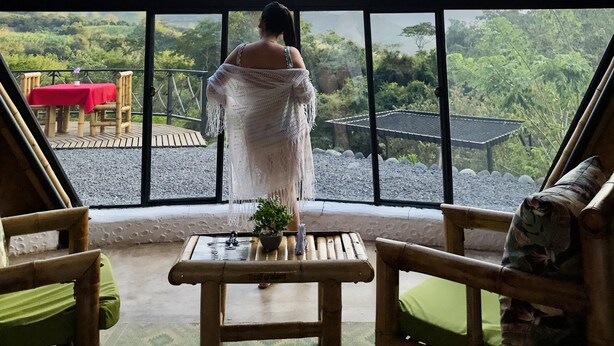 A view from a room with a large window, a table with a potted plant, and two chairs. - Ecofuratena Glamping (Utica)