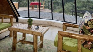A room with a large window offering a view of a red-roofed table and chairs on an outdoor deck. - Ecofuratena Glamping (Utica)