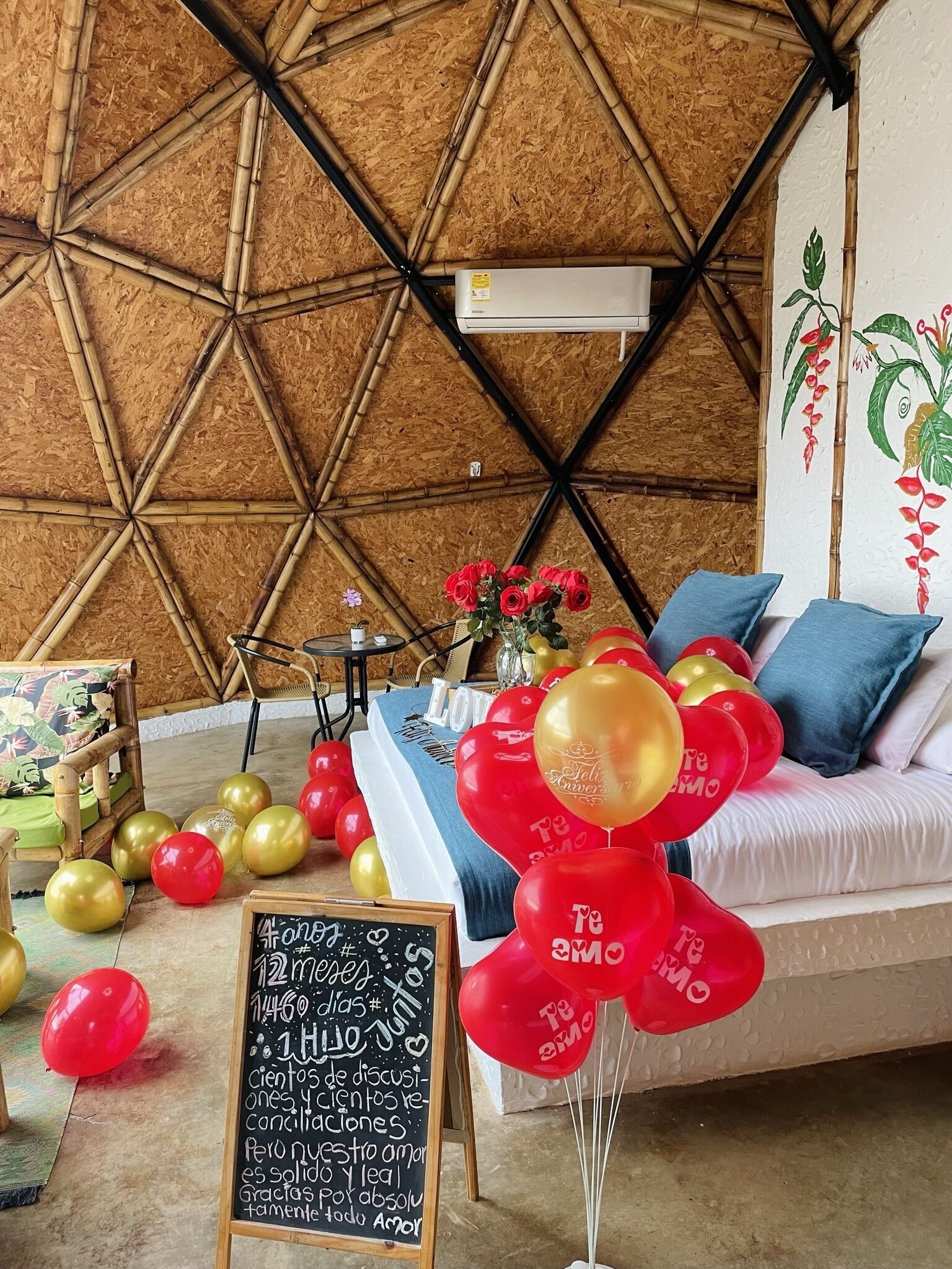 A cozy room with a geometric bamboo wall, a sofa with blue cushions, and a table with a floral arrangement.