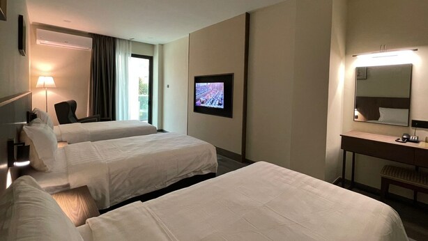 A hotel room with two beds, a desk, a chair, a TV, and a large mirror. - HOTEL BUNDUSAN (Kota Kinabalu)
