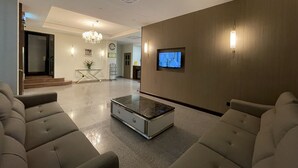 A modern living room with a television, a chandelier, and a coffee table. - HOTEL BUNDUSAN (Kota Kinabalu)