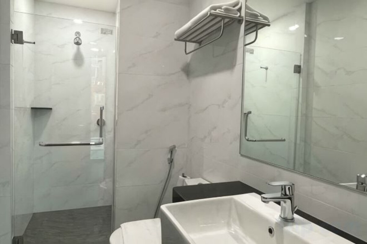 Une salle de bain moderne avec une douche à parois de verre, un lavabo blanc et un grand miroir.