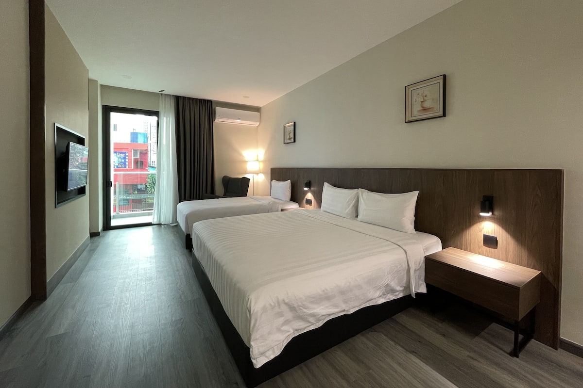 Ein Hotelzimmer mit einem großen Bett, Nachttischen, einem Fernseher und Blick nach draußen.