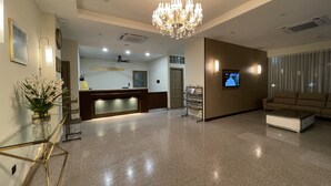 A hotel reception area with a chandelier, a reception desk, a television, and a sofa. - HOTEL BUNDUSAN (Kota Kinabalu)