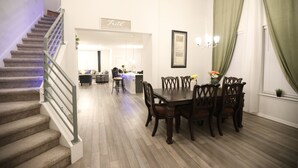 A dining area with a wooden table and chairs, a staircase with a metal railing, and a kitchen in the background. - Family and group friendly large, spacious modern home in Leander (Andice)