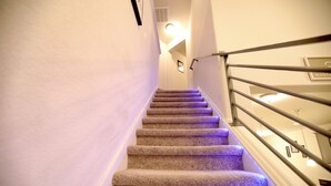 A carpeted staircase with a metal handrail and wall-mounted lights. - Family and group friendly large, spacious modern home in Leander (Andice)