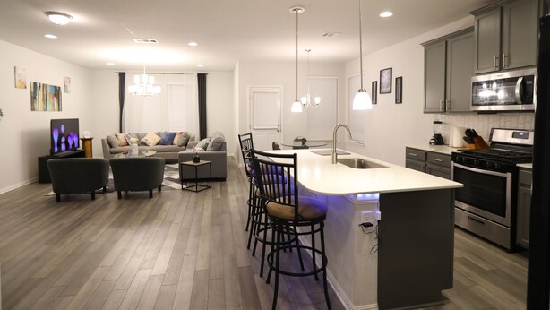 A modern kitchen with a central island, built-in appliances, and a dining area with bar stools. - Family and group friendly large, spacious modern home in Leander (Andice)