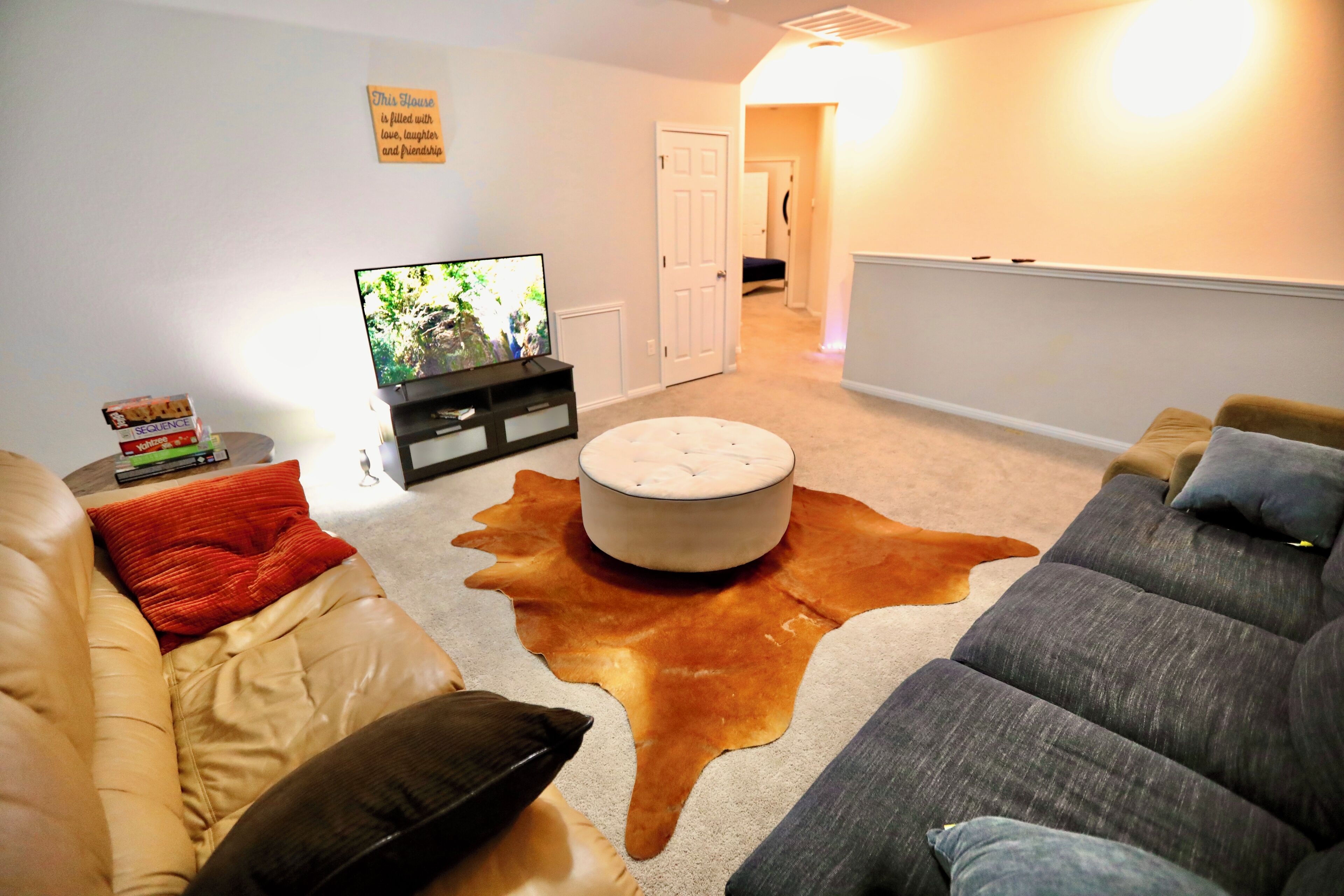A living room with a television, a sofa, a coffee table, and a cowhide rug.