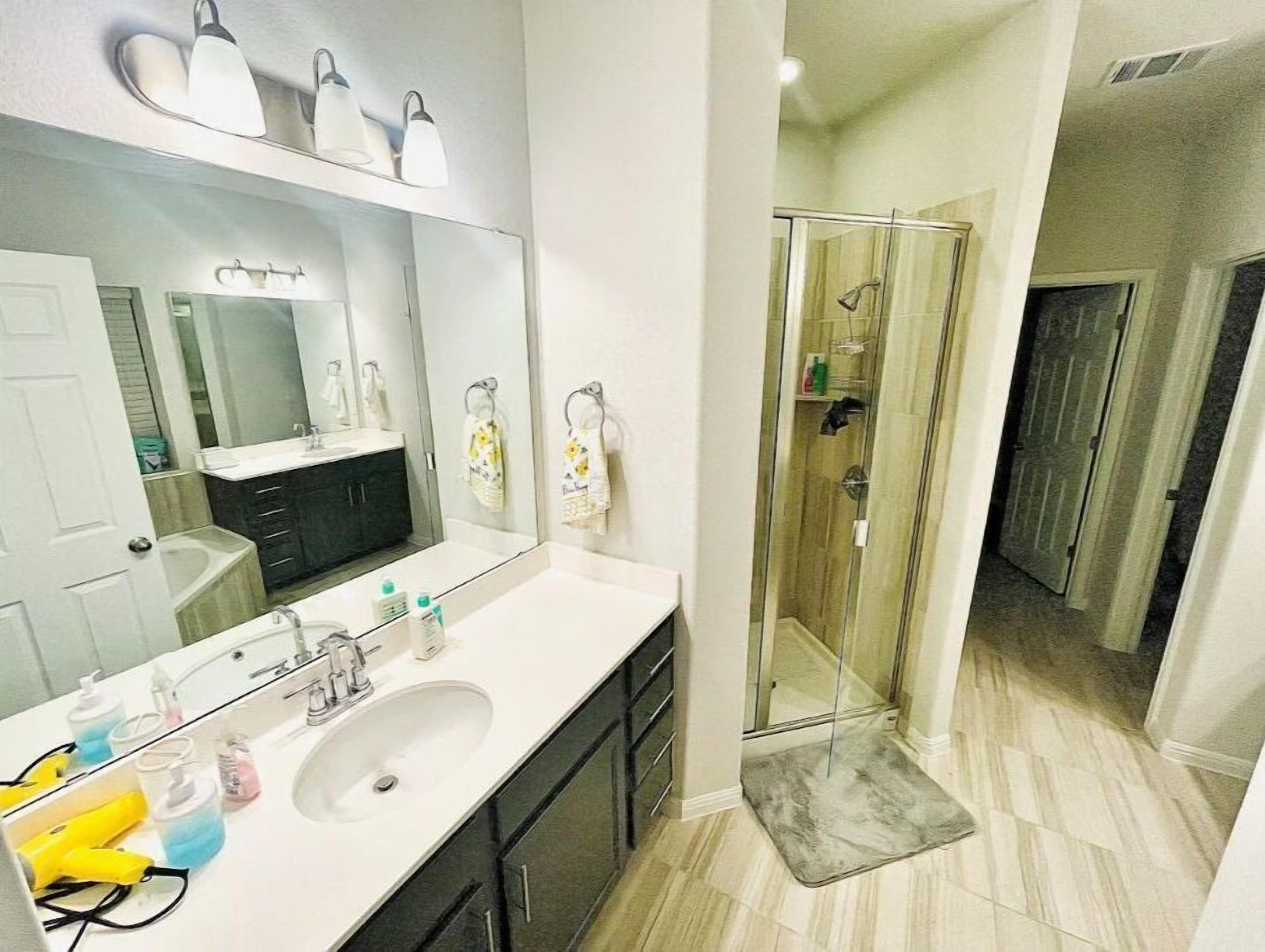 Un baño moderno con un espejo grande, un lavamanos y una zona de ducha.