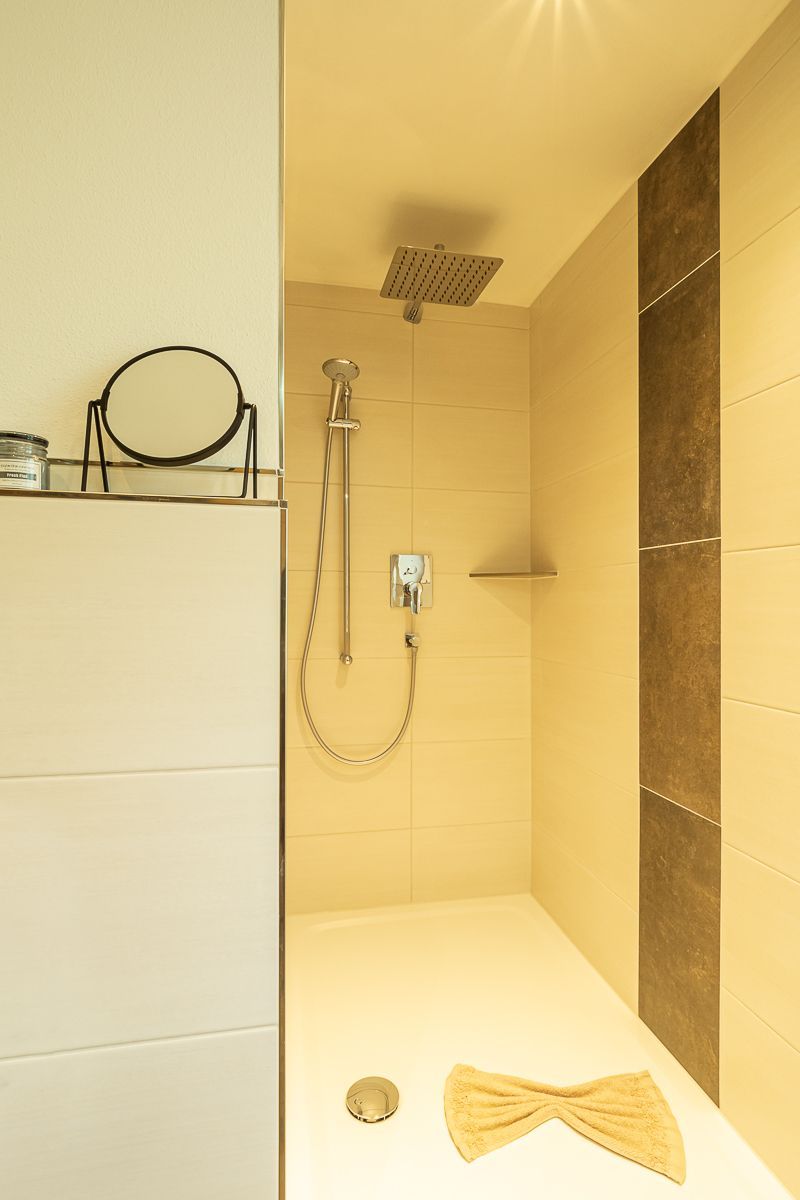 Ein Badezimmer mit Dusche, Handtuch und Spiegel.