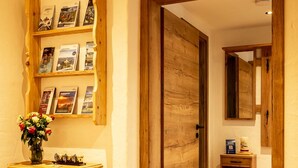 Een houten gang met een houten dressoir en een plank met ingelijste foto's.