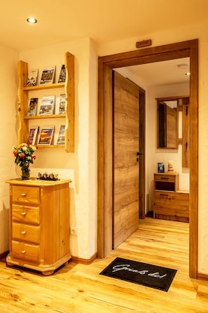 Ein Holzboden-Flur mit einer Holzkommode und einem Regal mit gerahmten Bildern.
