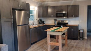 Eine moderne Küche mit Edelstahlgeräten, dunklen Holzschränken und einem Holztisch mit einer grünen Tischdecke.