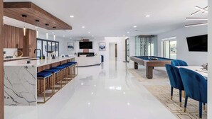 A modern kitchen with a marble countertop, a pool table, and a bar area with stools. - Multimillion $ ResortVilla+Waterslide+Pickleball+ (Scottsdale)