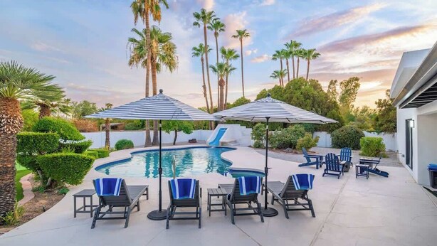 A pool area with lounge chairs, umbrellas, and palm trees. - Multimillion $ ResortVilla+Waterslide+Pickleball+ (Scottsdale)