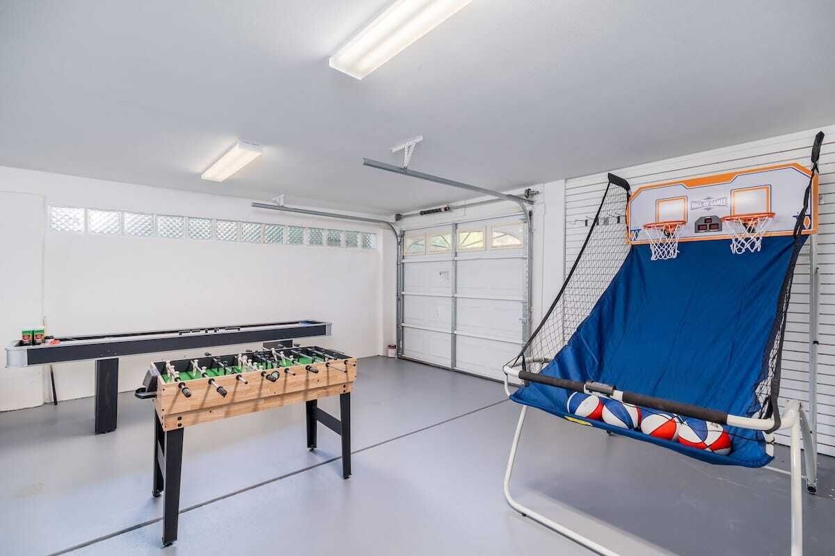 Une pièce équipée d’un baby-foot, d’un panier de basket et d’un espace délimité par un filet pour pratiquer des sports.