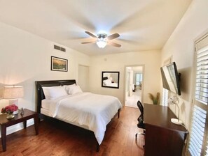 Simple, stylish room with a single bed, desk, and flat-screen TV.