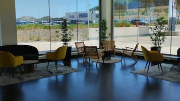 Un interior moderno con una zona de estar, ventanas amplias y vistas a un estacionamiento.