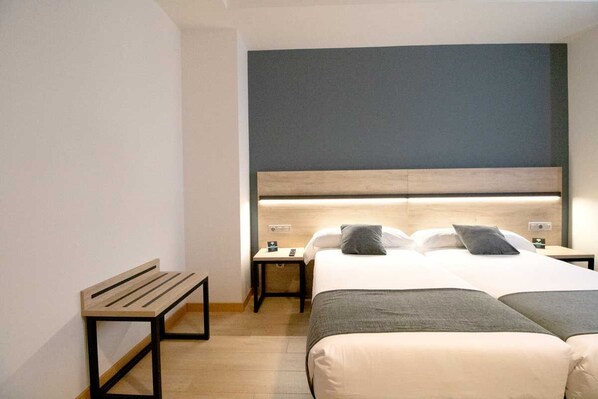 A hotel room with a bed, bedside tables, a bench, and a headboard.