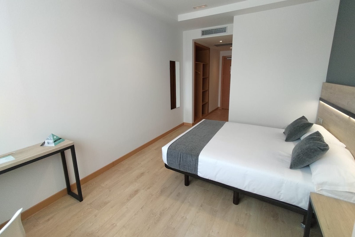 A bedroom with a bed, bedside table, and a wardrobe.
