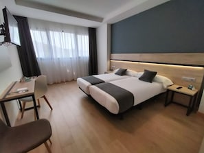 A modern hotel room with a large bed, a desk, and a chair. - Alda Valladolid Sur (Valladolid)
