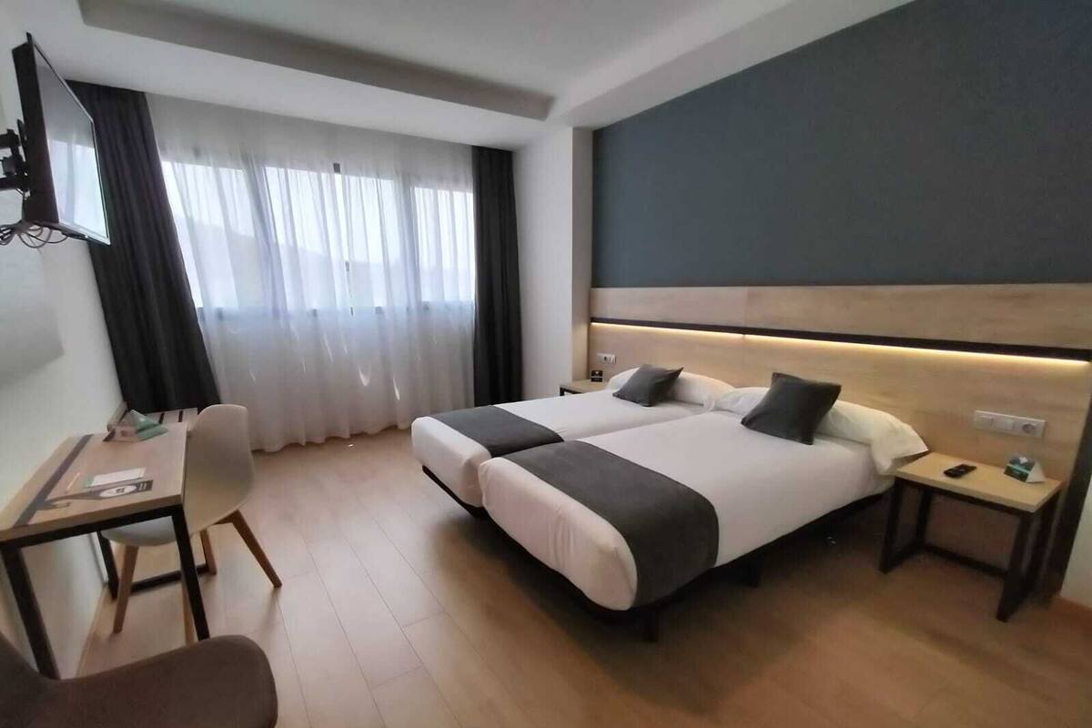 Quarto de hotel moderno com uma cama grande, uma escrivaninha e uma cadeira.
