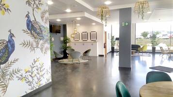 Un interior moderno con un mostrador de recepción, zona de estar y decoración en la pared.