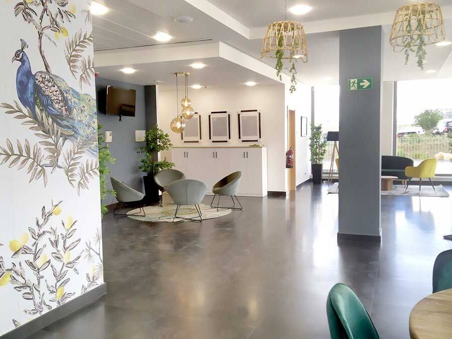 Un interior moderno con un mostrador de recepción, zona de estar y decoración en la pared.