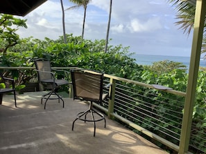 Relax in this ocean-view seating area with two comfortable chairs and a table, surrounded by lush greenery.