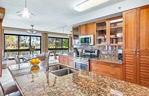 Una cucina moderna con piani in granito, elettrodomestici in acciaio inox e mobili in legno.