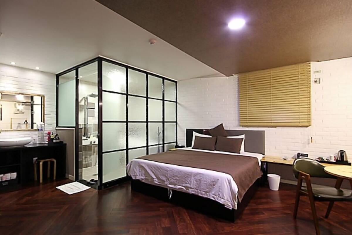 A modern bedroom with a large bed, a desk, and a walk-in closet.