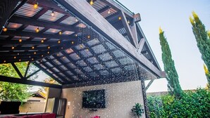 A covered outdoor area with a wooden roof, string lights, and a television screen. - The Grand Resort, 1 Acre Property.
"Huge Outdoor Space to Relax in the Sun!" (gilbert)