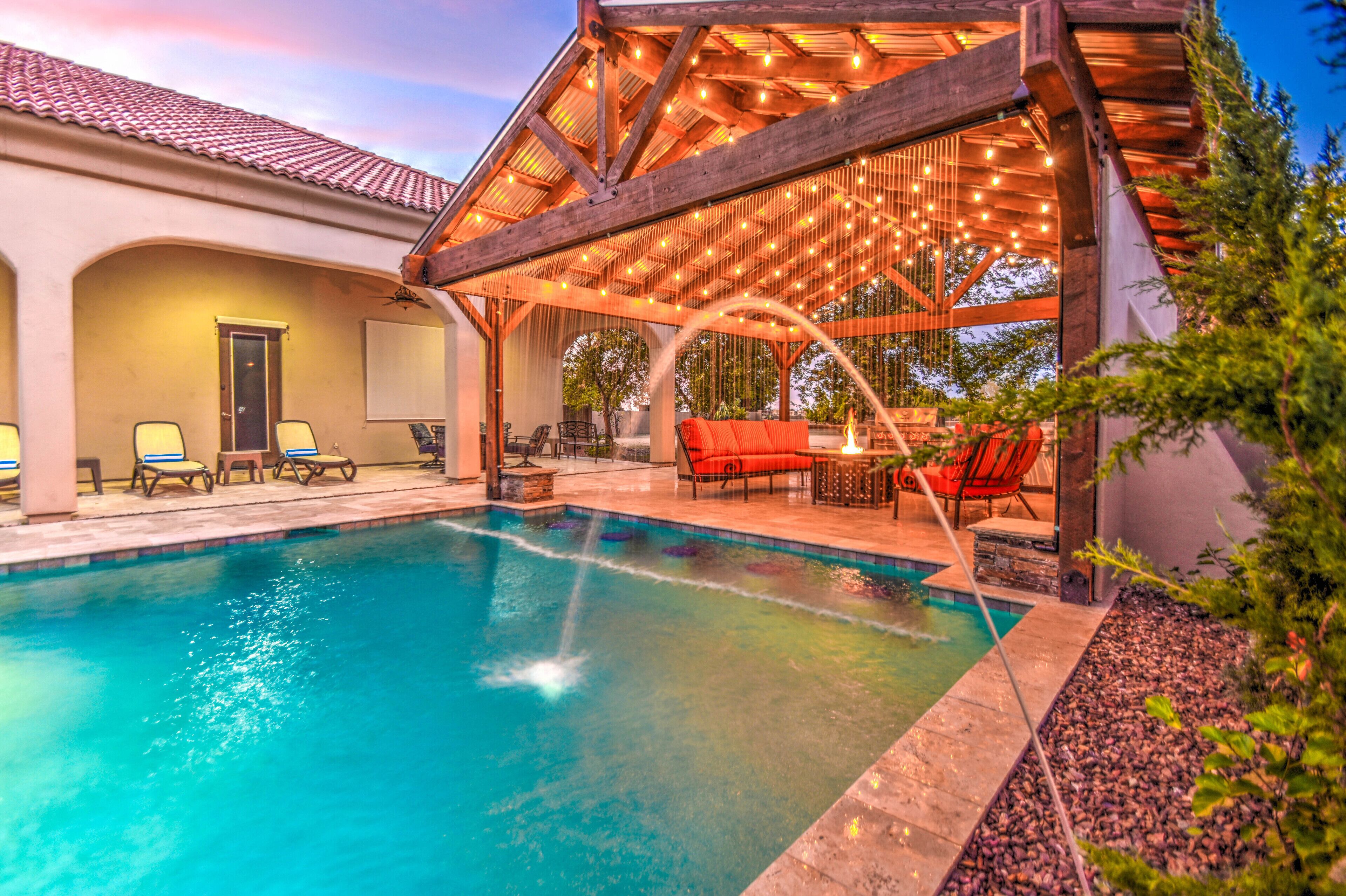 A swimming pool with a wooden deck and lounge chairs, surrounded by a landscaped garden.