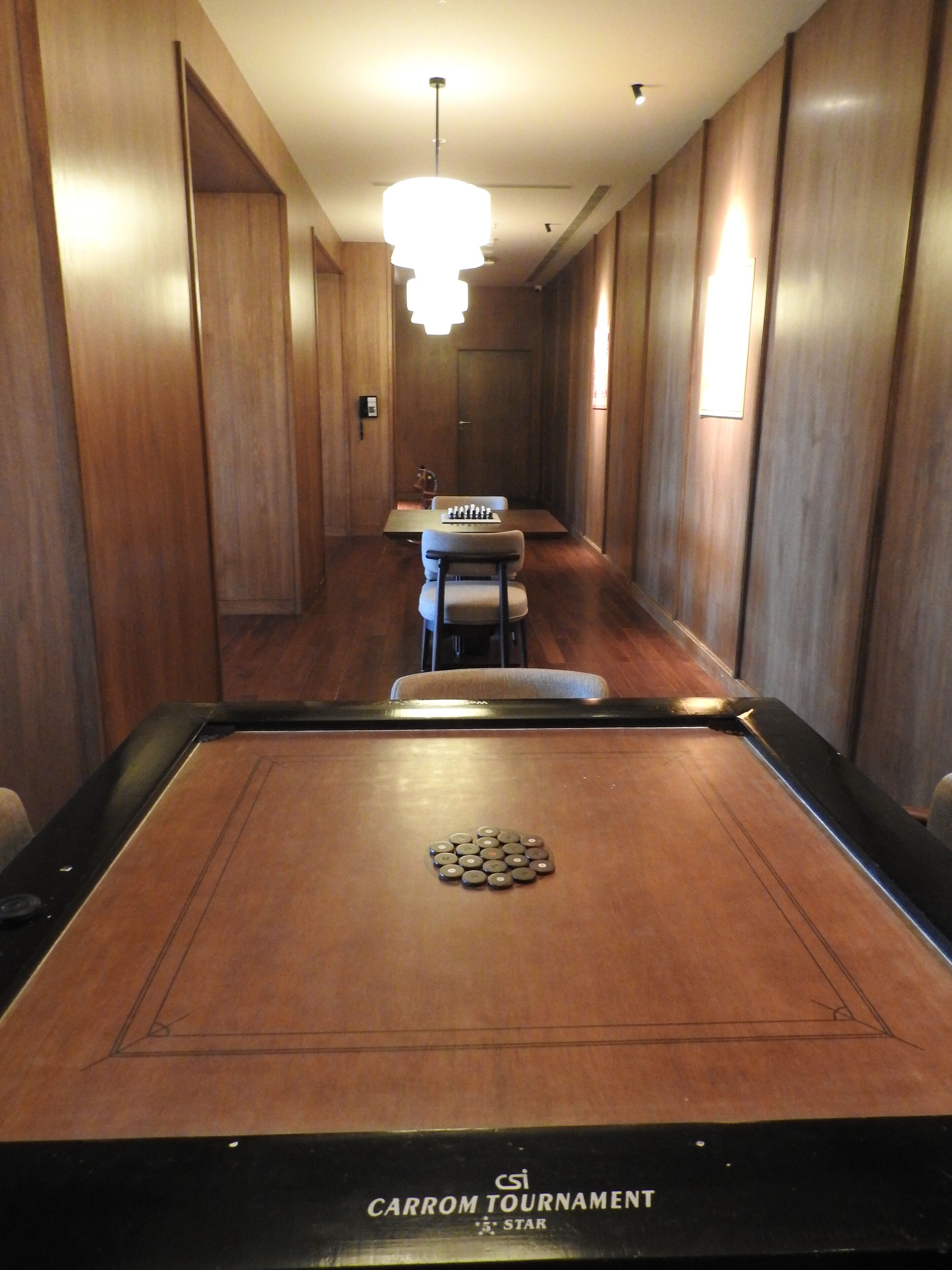Una mesa de billar con un logo de estrella, una mesa de comedor con sillas y una araña en una sala con paneles de madera.