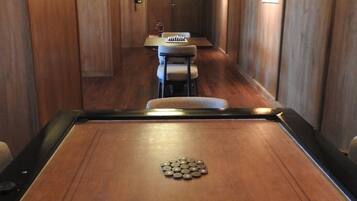 Una mesa de billar con un logo de estrella, una mesa de comedor con sillas y una araña en una sala con paneles de madera.