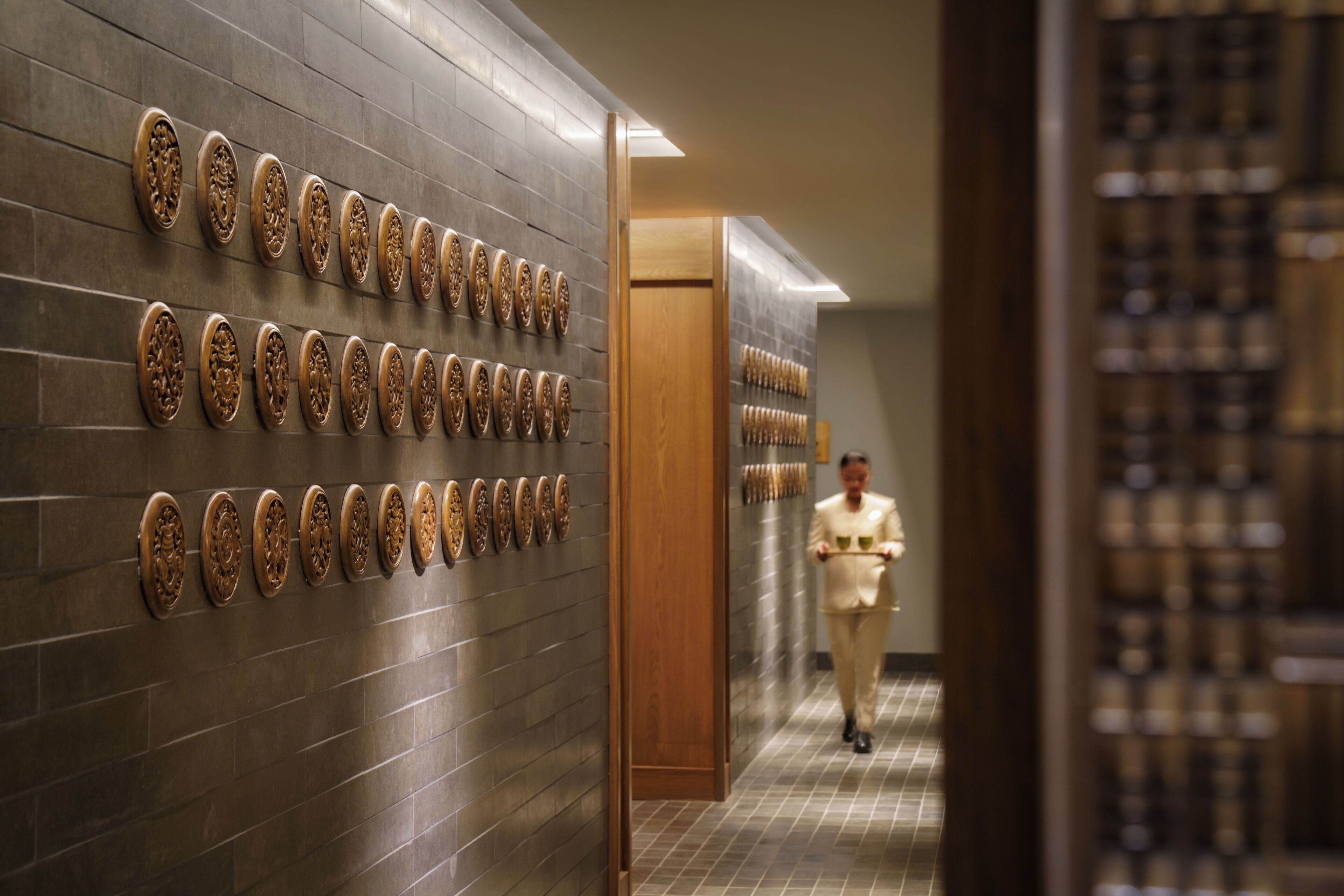 A hallway with a patterned wall and a wooden door.