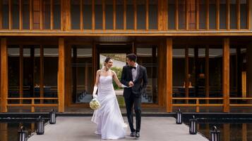 A couple walking hand in hand in front of a building with wooden columns and large windows.