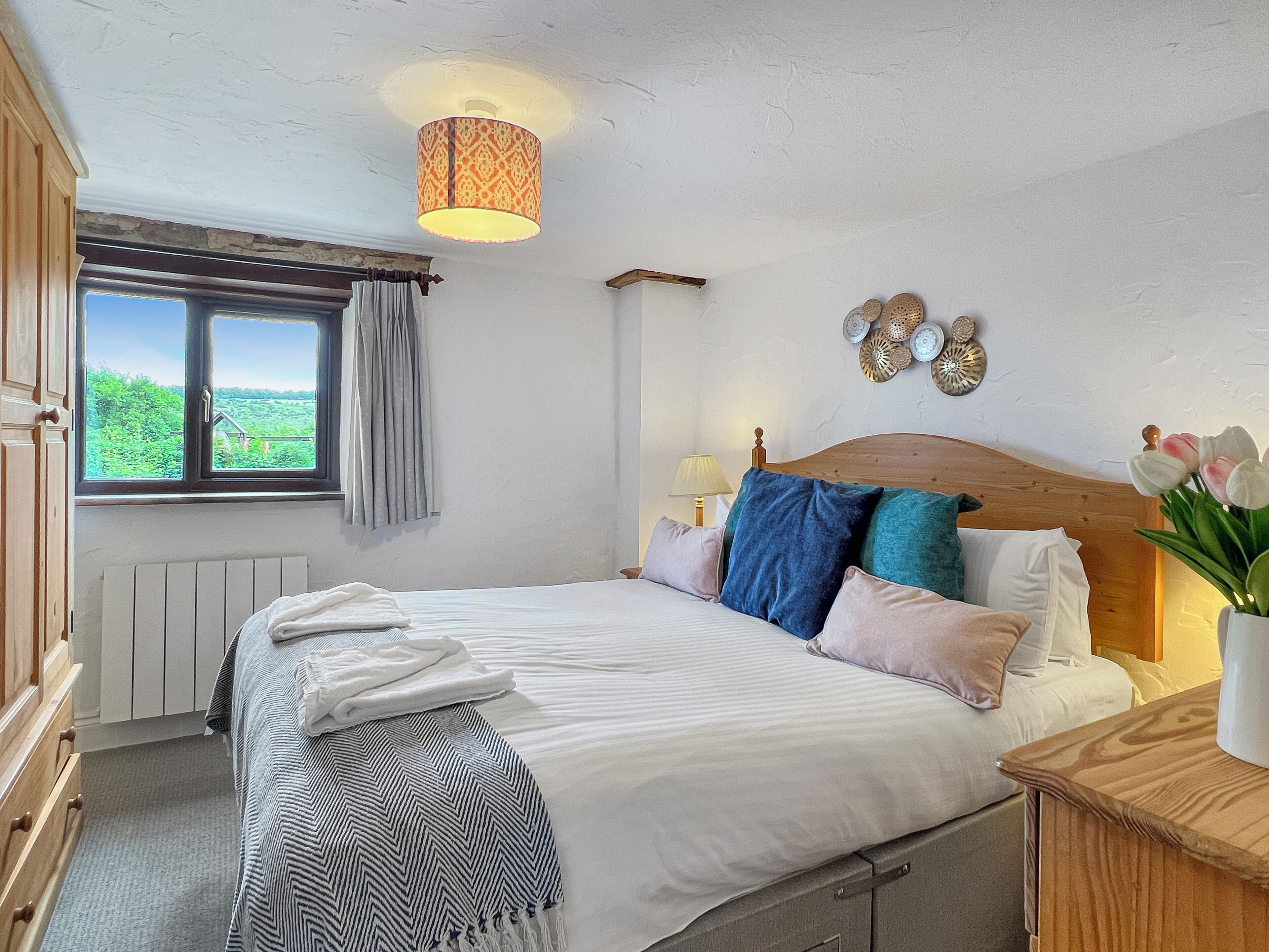 A bedroom with a bed, a window with curtains, a lamp, and decorative wall art.