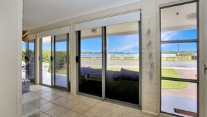 A room with large sliding glass doors leading to a balcony with a view of the sea and boats.