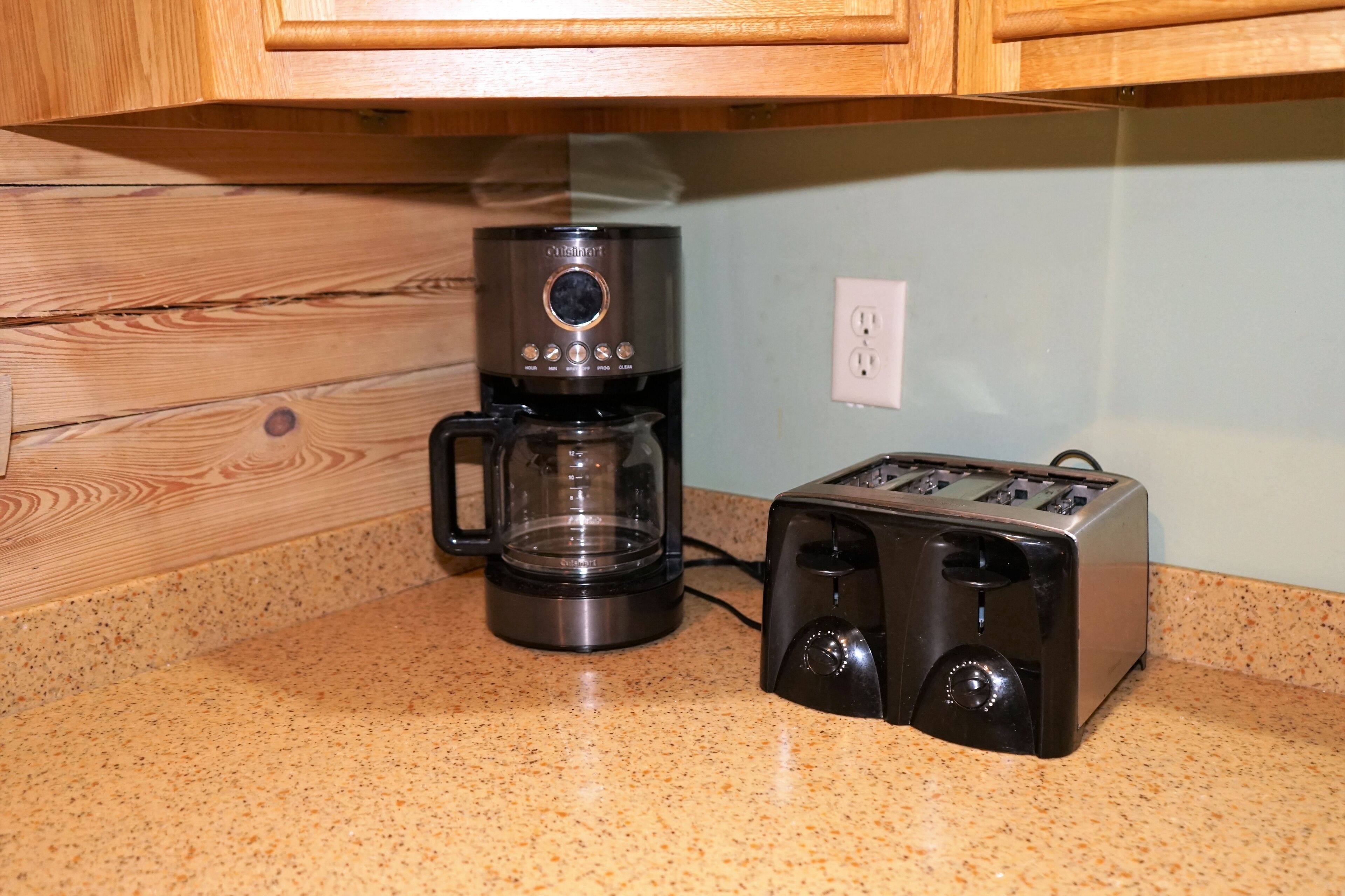 A kitchen with a coffee maker and a toaster on a speckled countertop.
