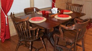 A wooden dining room with a table set for six, red curtains, and nautical-themed decor. - Secluded, peaceful Coastal Log Cabin with hot tub. (Townsend)